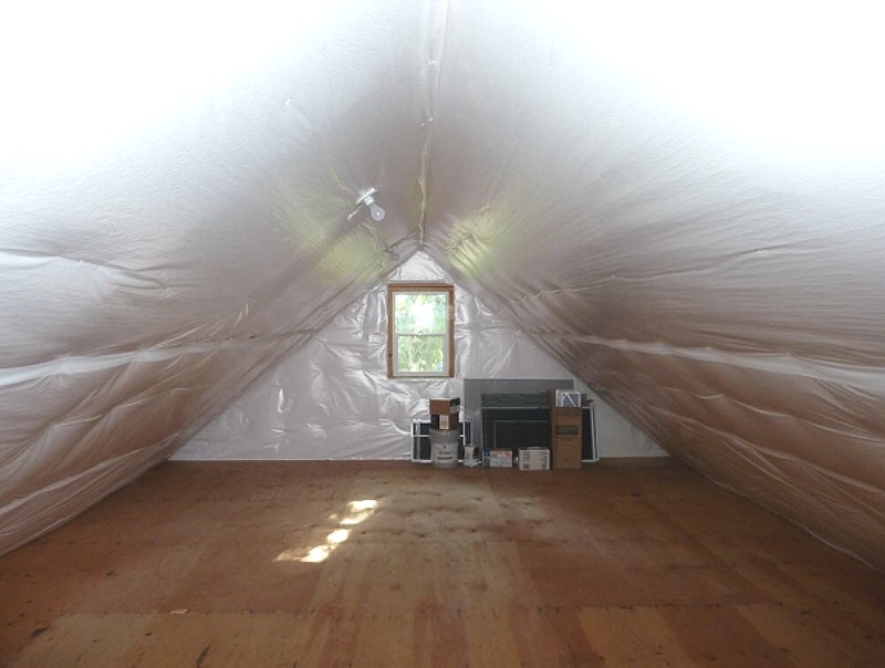 attic with the rafters and end walls wrapped in insulation and a window in the gable